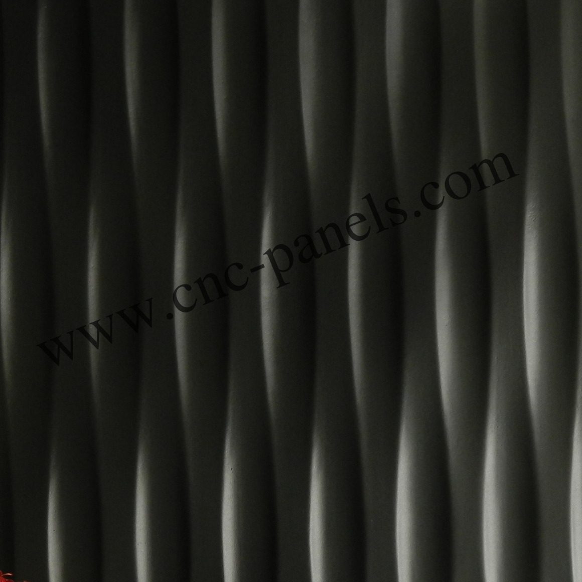 PAN052 PAN 052 charcoal wave wall panel — deep vertical wave texture in matte graphite finish, shown with red flowers in white planter